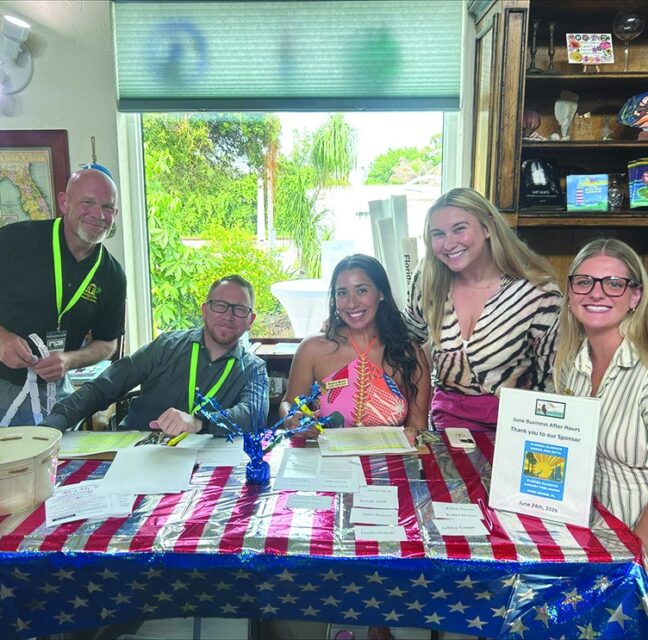 Chamber ambassadors checking in members at a flag-draped table at Florida Classics Books