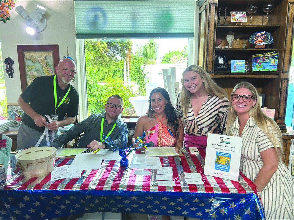 Chamber ambassadors checking in members at a flag-draped table at Florida Classics Books