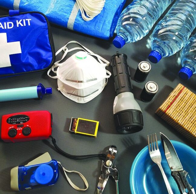 First aid kit, bottled water, flashlights, radio and canned food laid out as a hurricane kit