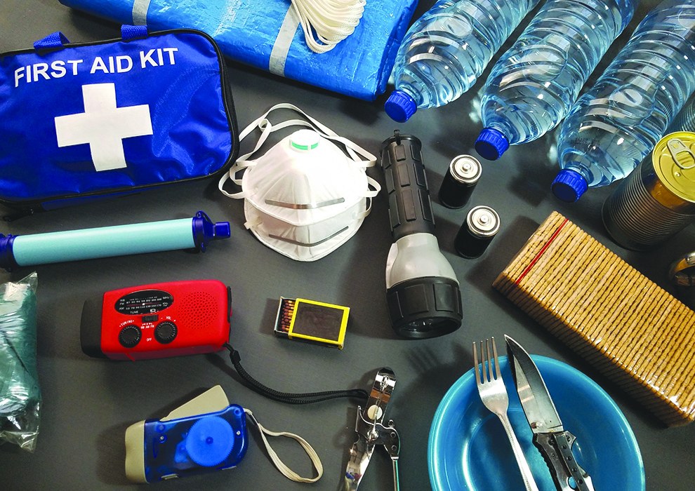 First aid kit, bottled water, flashlights, radio and canned food laid out as a hurricane kit