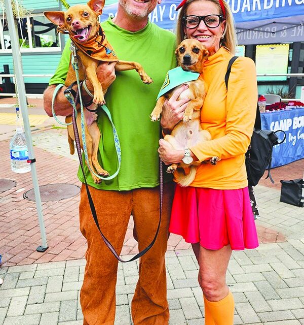 Kevin and Vanessa Herrera in costume holding their dogs at the Pup Crawl