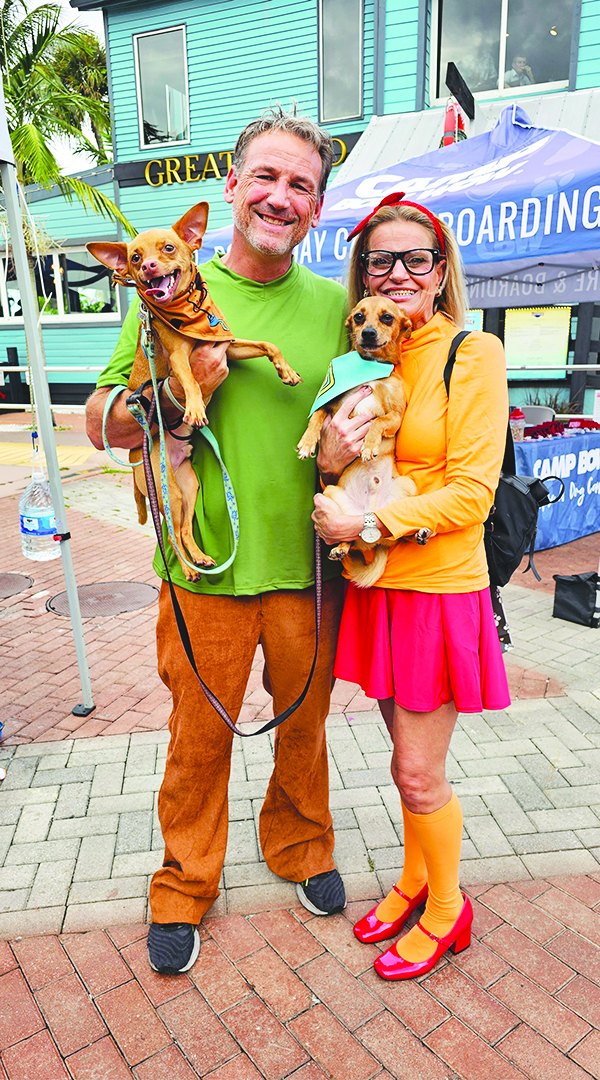 Kevin and Vanessa Herrera in costume holding their dogs at the Pup Crawl